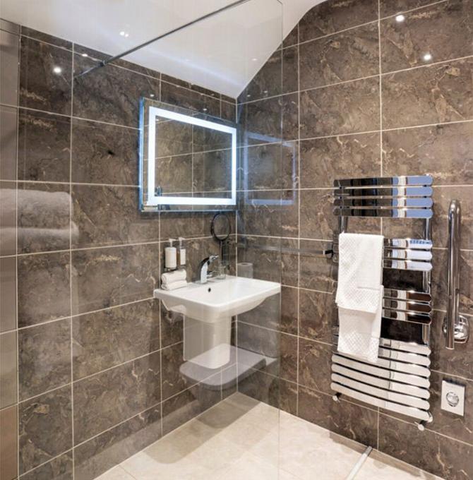 Ensuite in hotel room with shower, sink and radiator