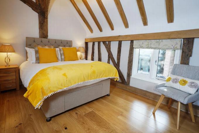 Double bed in room with wooden beams and chair